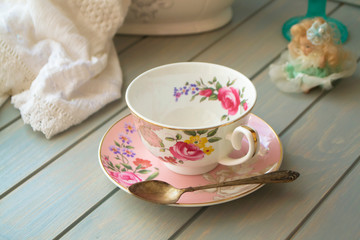 Pink antique porcelain tea cup on turquoise table.