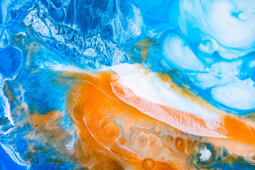 Fluid art texture. Background with abstract iridescent paint effect. Liquid acrylic artwork that flows and splashes. Mixed paints for posters or wallpapers. Blue, golden and white overflowing colors