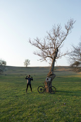 Cyclist in shorts and jersey on a modern carbon hardtail bike with an air suspension fork standing on a cliff against the background of fresh green spring forest