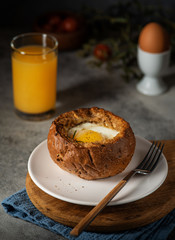 Baked Egg inside a bun. Breakfast with Eggs and Orange Juice.