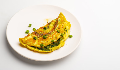Omelet with spinach, green onions and cherry tomato on a white plate.