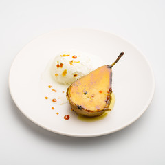 Caramelized pear with vanilla ice cream on a white plate. Close-up