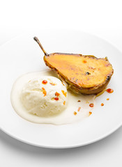 Caramelized pear with vanilla ice cream on a white plate. Close-up