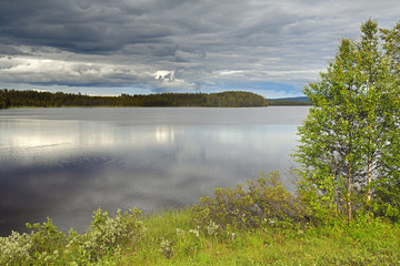 Summer landscape with black clouds. Forest Lake. Finnish Lapland, Suomi