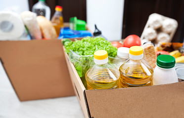 The full cardboard eco box with products from the grocery store on the floor at home near the door