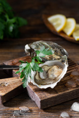 Two oysters on a wooden Board against the background of a basket of oysters