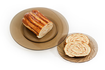 Piece and slices of Swiss roll on dark glass dishes