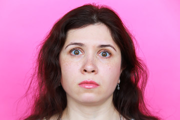 Surprised scared young woman on pink background