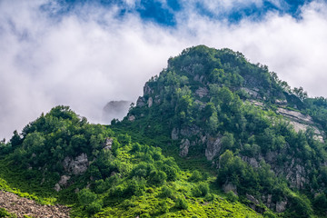 Fototapeta premium Green mountain slope with rocks on cloudy day.