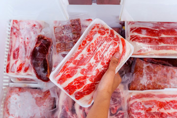 Hand choosing fresh raw yakiniku meat in freezer