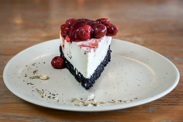 Slice of plain cheesecake with strawberry sauce on white plate.
