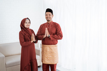 Asian couple smile standing up with gestures of apologize when wish Happy Ramadan Kareem