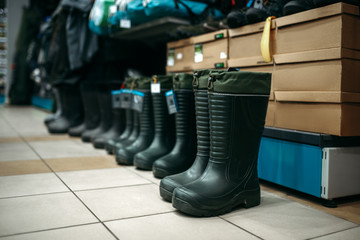 Fototapeta na wymiar Row of rubber boots in fishing shop, nobody