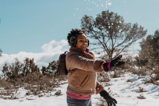 African American Black Woman Playing With The Snow, Wearing Bag, Gloves, Earmuffs.