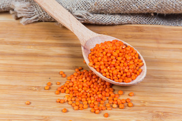 Raw red lentil in wooden spoon on a wooden surface
