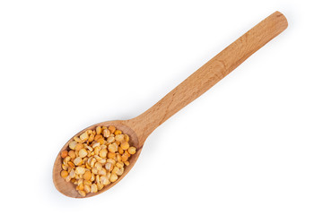 Yellow split peas in wooden spoon on a white background