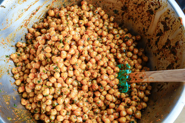 Marinated and cooked chickpeas with spices in a bowl for mixing with a spatula.