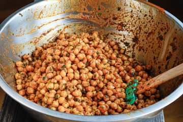 Marinated and cooked chickpeas with spices in a bowl for mixing with a spatula.
