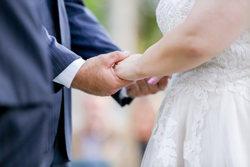 Obraz na płótnie Canvas Wedding couple holds hands during ceremony as they say 