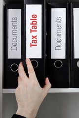Tax Table– finance/economics. File Folder is taken from office shelf. Male hand. Business, statistics