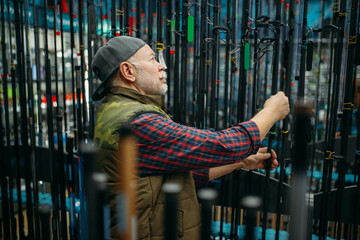 Fototapeta na wymiar Male angler choosing rod in fishing shop