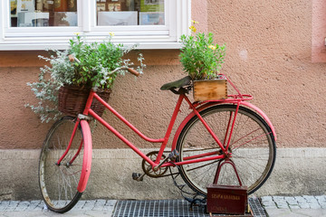 Fototapeta na wymiar GDANSK, POLEN - 2016 SEPTEMBER 14. An old stylized red bike with baskets full of flowers standing on the street.