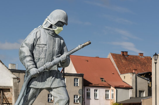 KARLINO, WEST POMERANIAN / POLAND - 2020: Figure of a fireman from a fountain in a city square in a protective mask against coronavirus