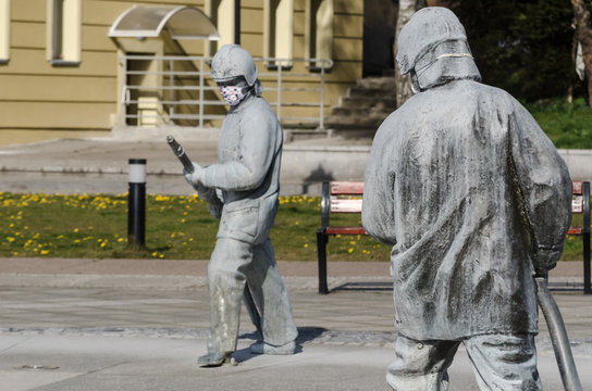 KARLINO, WEST POMERANIAN / POLAND - 2020: Figure of a fireman from a fountain in a city square in a protective mask against coronavirus