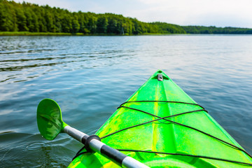 Beautiful nature scene on lake with green kayak. Kayaking on a lake.