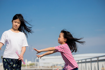 屋外でシャボン玉を遊んでいる子供姉妹