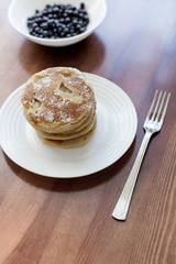pancakes with berries and powdered sugar in a white plate are on the table