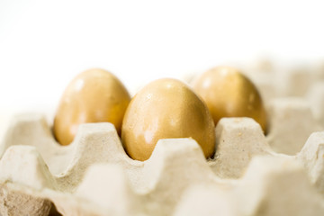 Three golden eggs on carton
