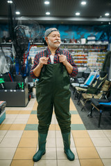 Fisherman tries on rubber jumpsuit in fishing shop
