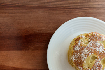 pancakes with berries and powdered sugar in a white plate are on the table