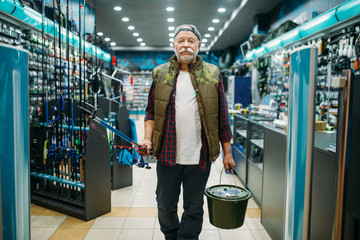 Fisherman with rod and bucket in fishing shop