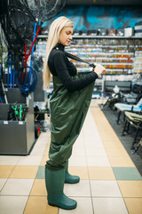 Female angler in rubber jumpsuit, fishing shop
