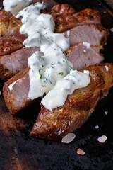 Grilled meat on wooden cutting board with white sauce