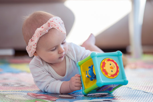 A cute young baby playing inside home with colorful toys