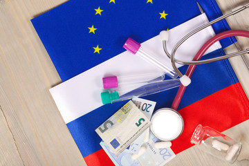 Medication,test tubes,money and stethoscope on European and Russian flags