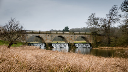 Fototapeta na wymiar Water flowing under a bridge next to fields