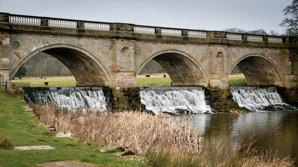 Water flowing under a bridge next to fields