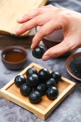 woman hand holing black sesame ball on bamboo plate with tea