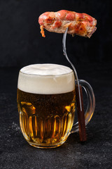 Glass of beer and fork with grilled sausage
