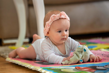 A cute young baby playing inside home with colorful toys