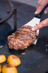 Man rotating over beef meat on a grill with spatula