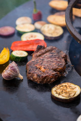 Close up of a beef steak and paprika, garlic, zucchini on a grill