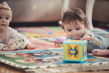 Fototapeta na wymiar cute twins, baby girl and baby boy playing with toys by the home