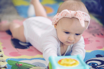 A cute young baby playing inside home with colorful toys