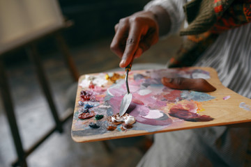 Painter holds brush and colorful paints on palette