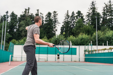 Athletic man hitting a ball while playing tennis outdoors